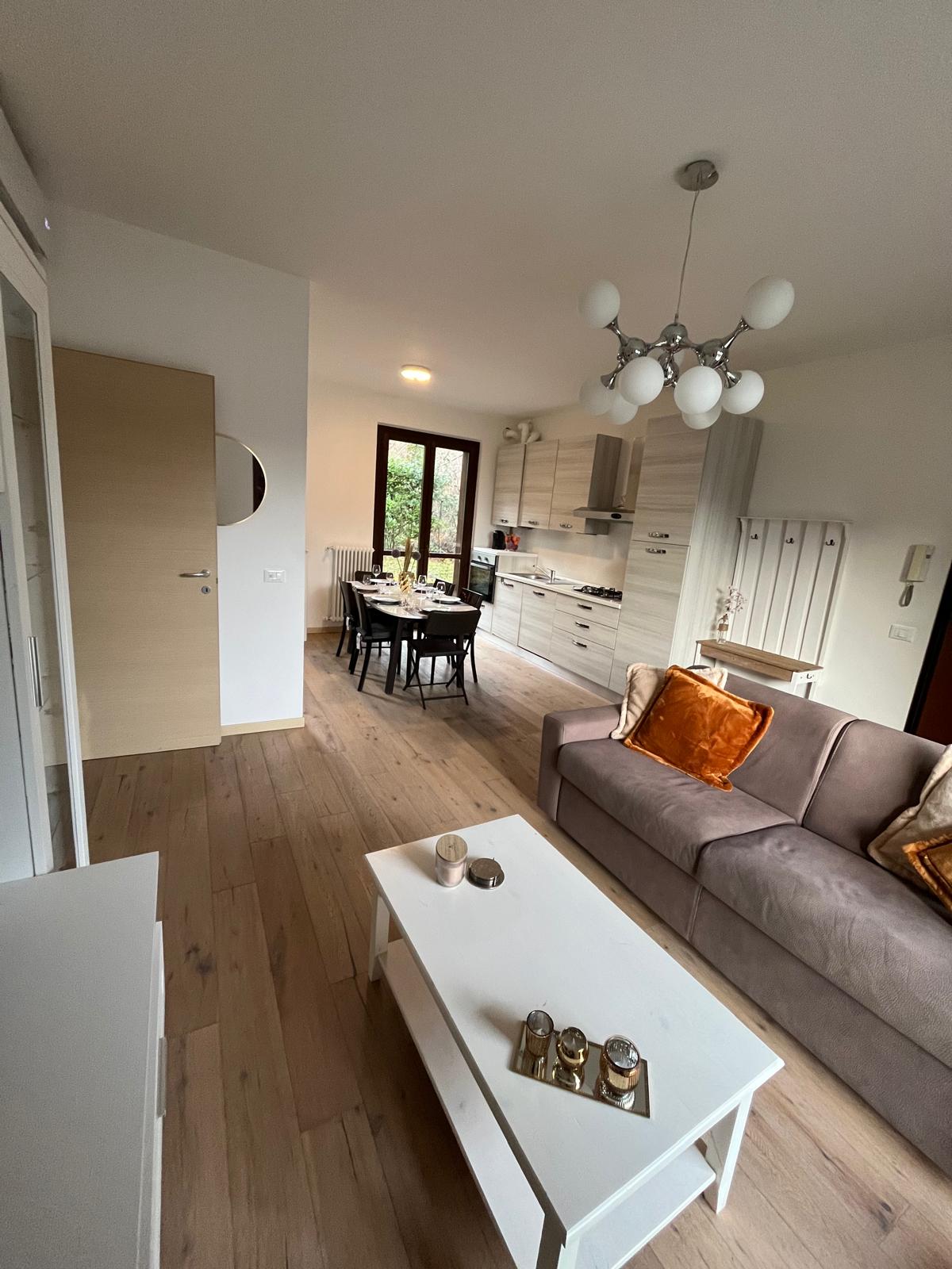 Woonkamer met zithoek, eettafel en keuken in het appartement in Argegno